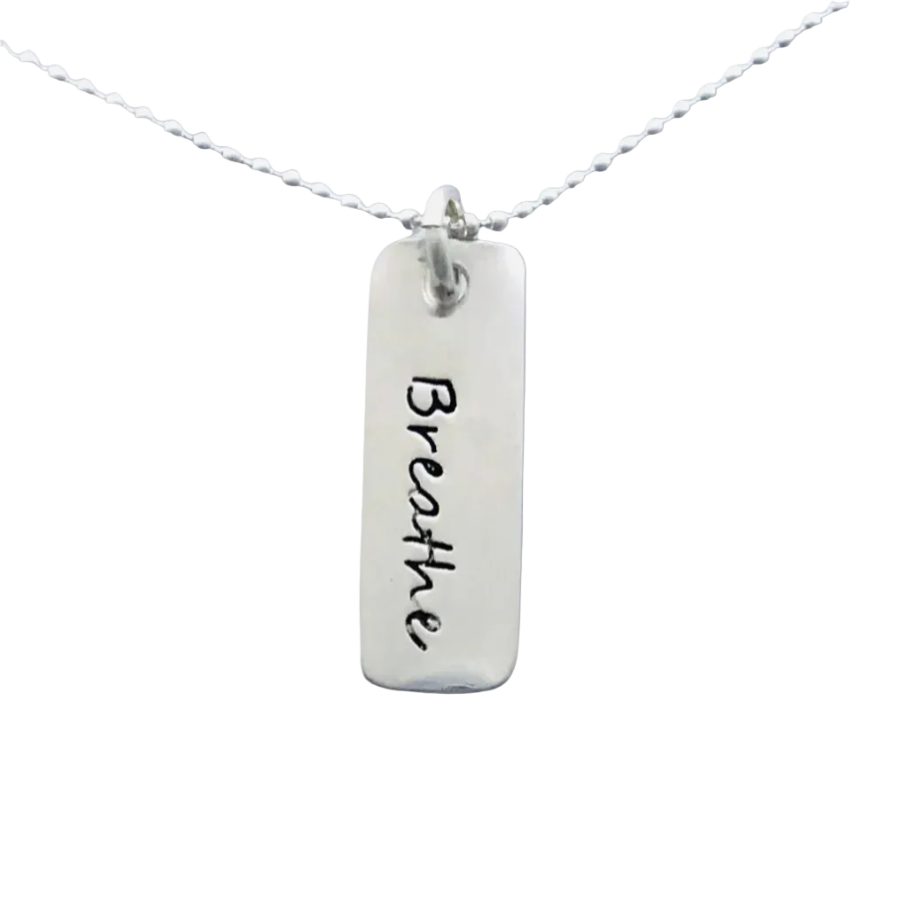 A sterling silver bar charm necklace with the word 'Breathe' hand-stamped on it, attached to a sterling silver chain.